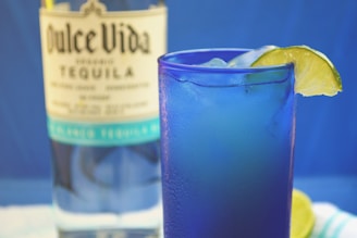 A vibrant cocktail with tequila garnished with lime.