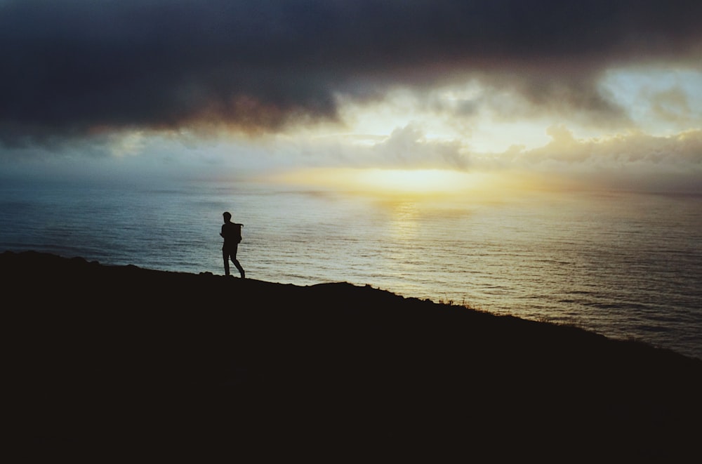 person walking beside body of water