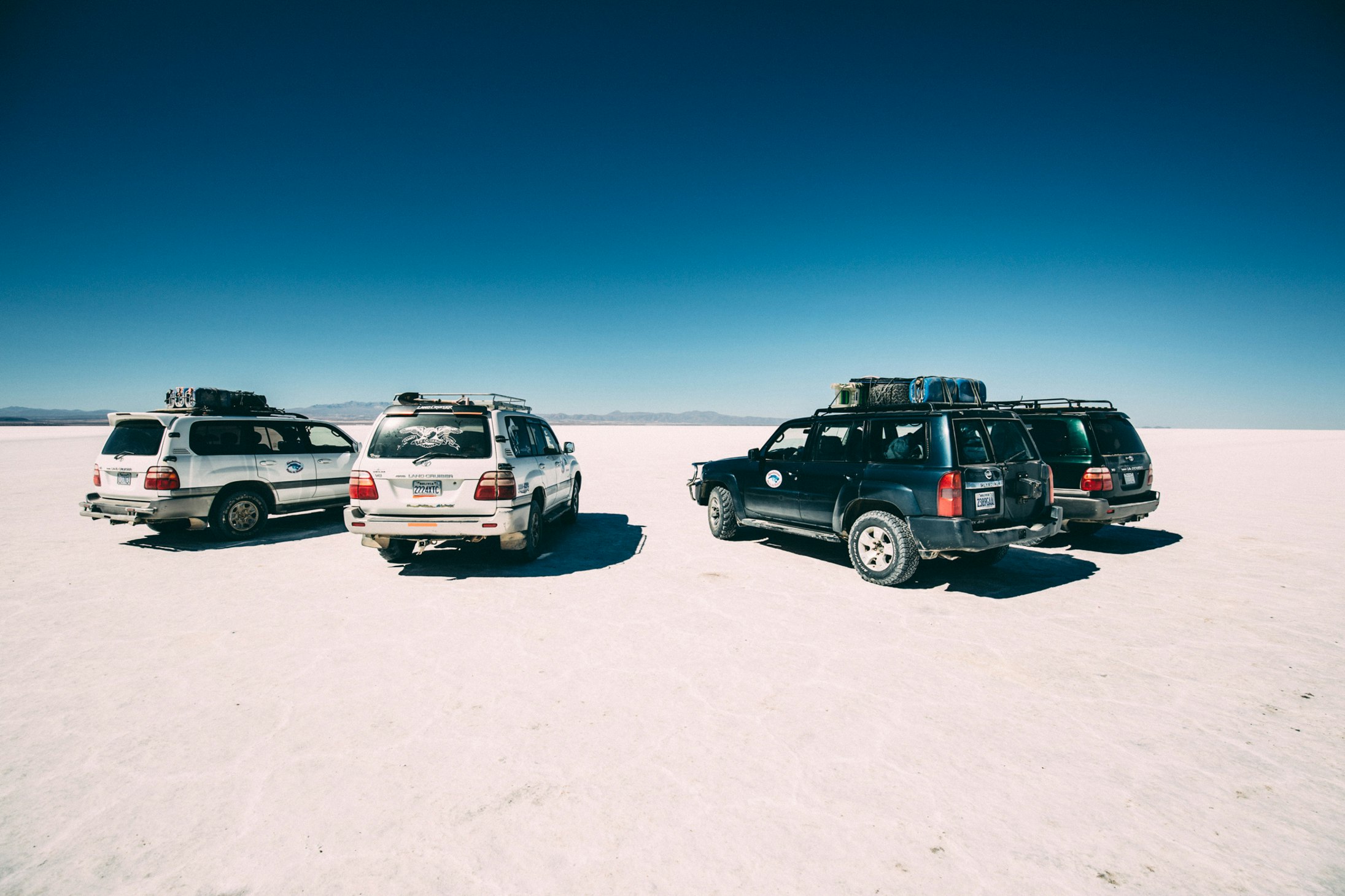 four vehicles on desert at daytime