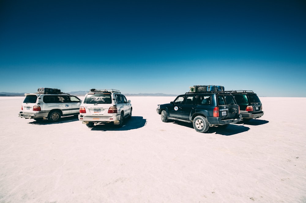 four vehicles on desert at daytime