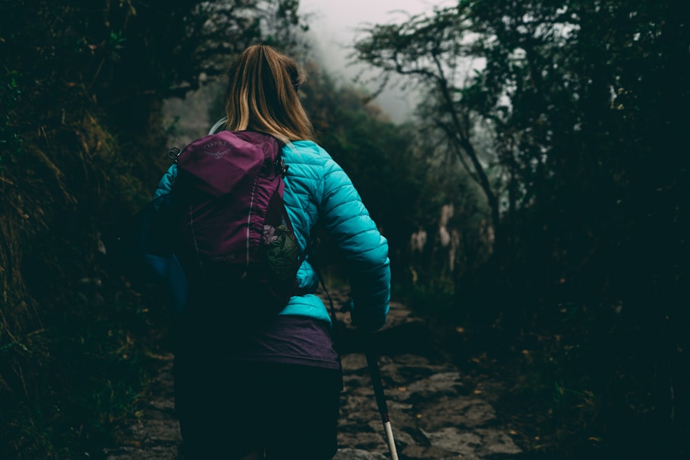 Mulher vestindo jaqueta de bolha andando no caminho entre a floresta