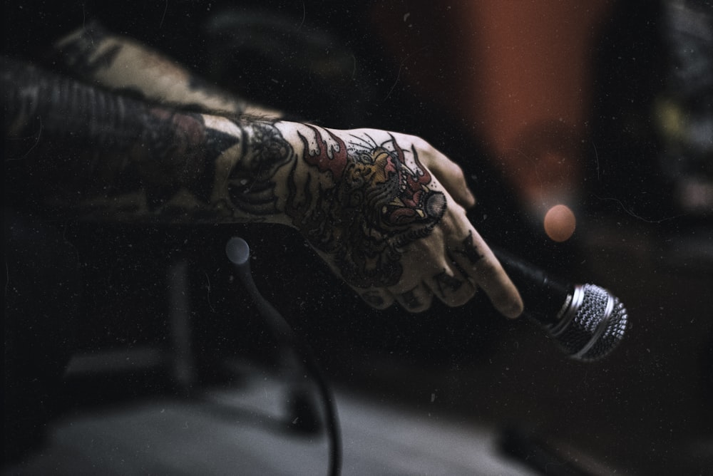 tattooed person holding microphone