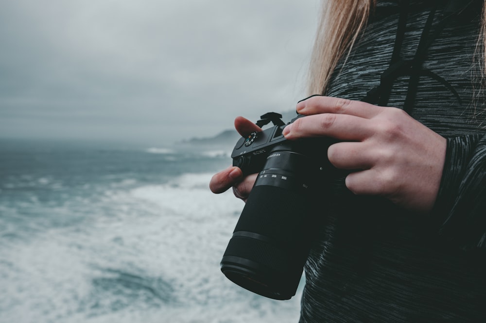 Fotografia a fuoco selettiva di donna che tiene la macchina fotografica