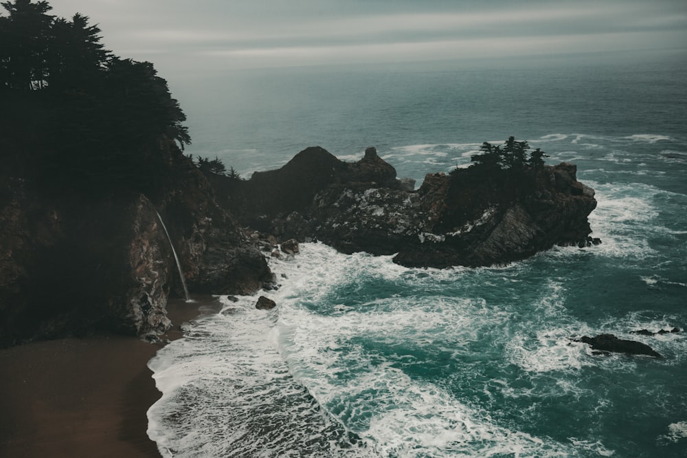 aerial photography of seawaves crashing seashore and rocks at daytime