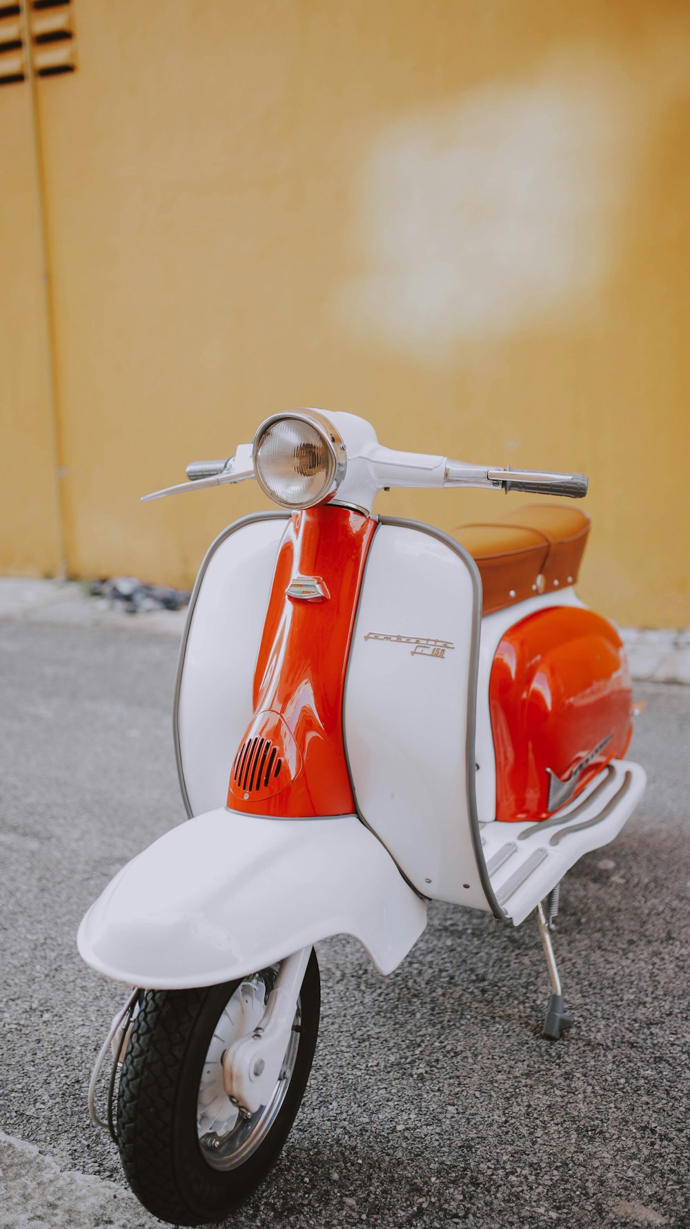 white and orange motor scooter on gray flooring