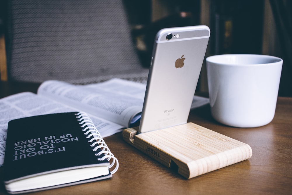 silver iPhone 6 beside white ceramic mug