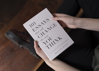 person holding 101 Essay that will Change the way you Think book