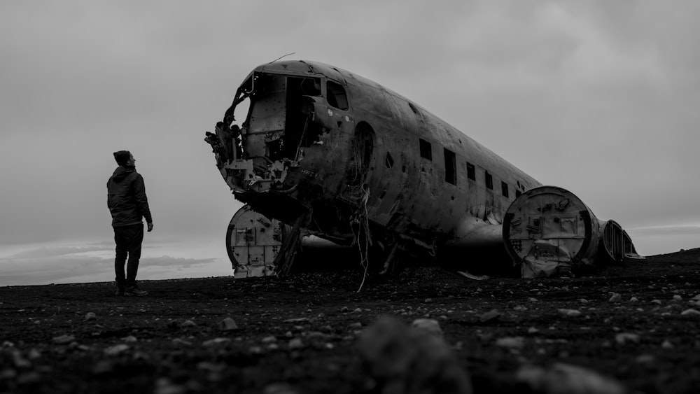 墜落した飛行機のそばに立つ男