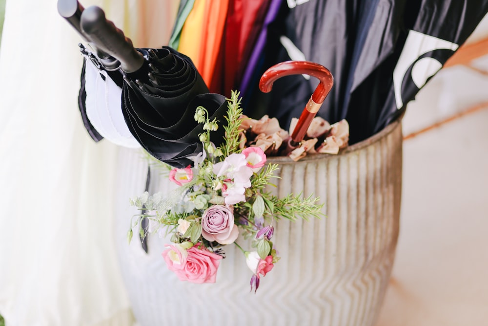 umbrellas inside white clay floor vase with pink petaled flowers in closeup shot