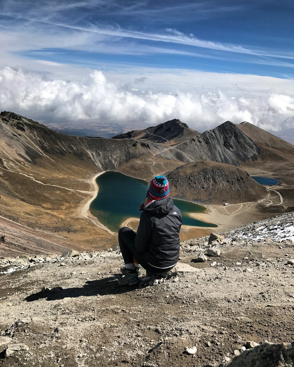 person sitting on stone on mountain