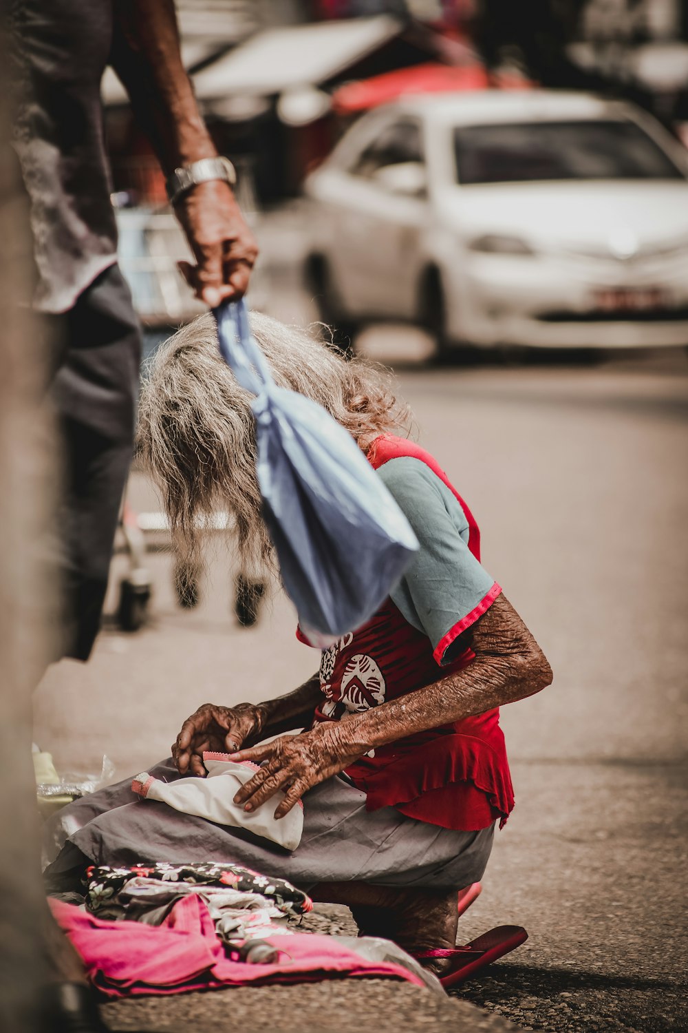 old woman kneeling on road