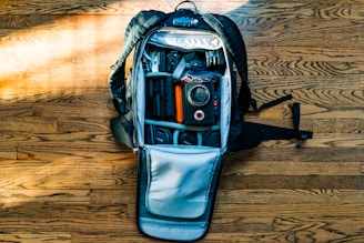 flat-lay photography of DSLR camera in backpack on wood parquet floor