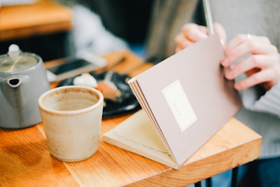 person opening book near coffee cip thoughtful zoom background