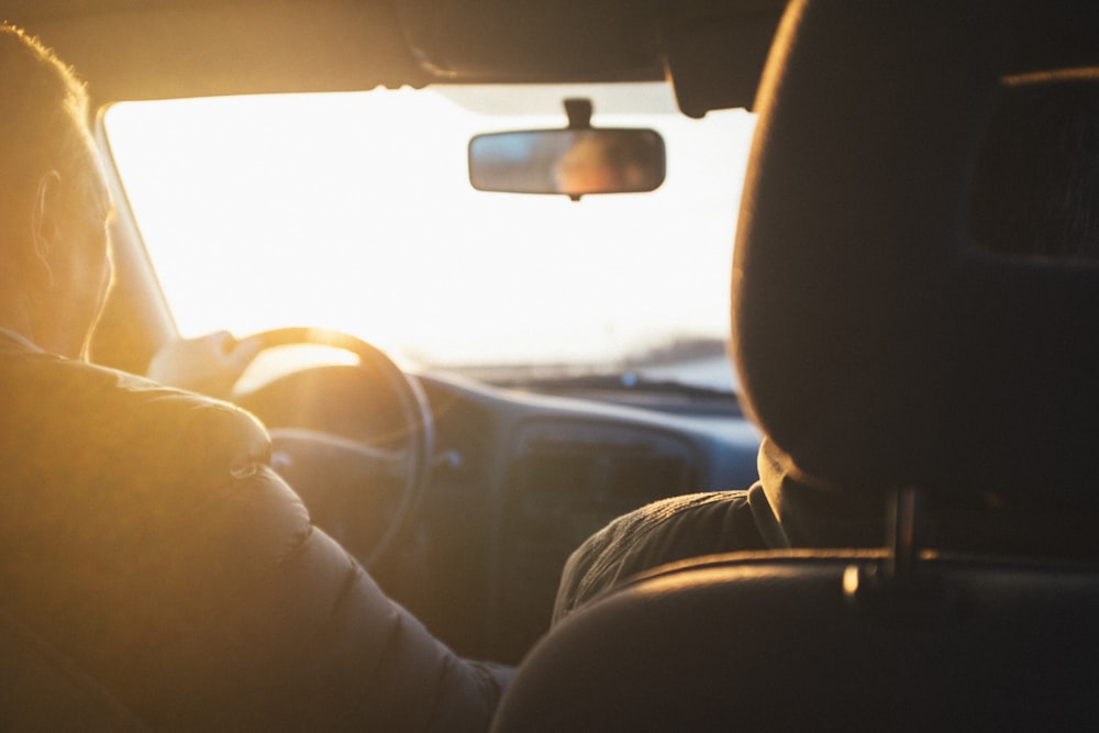 homme conduisant une voiture pendant l’heure dorée