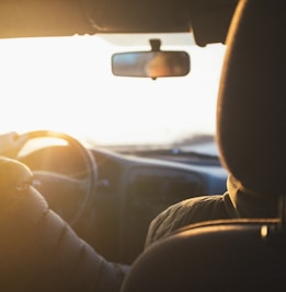 man driving car during golden hour