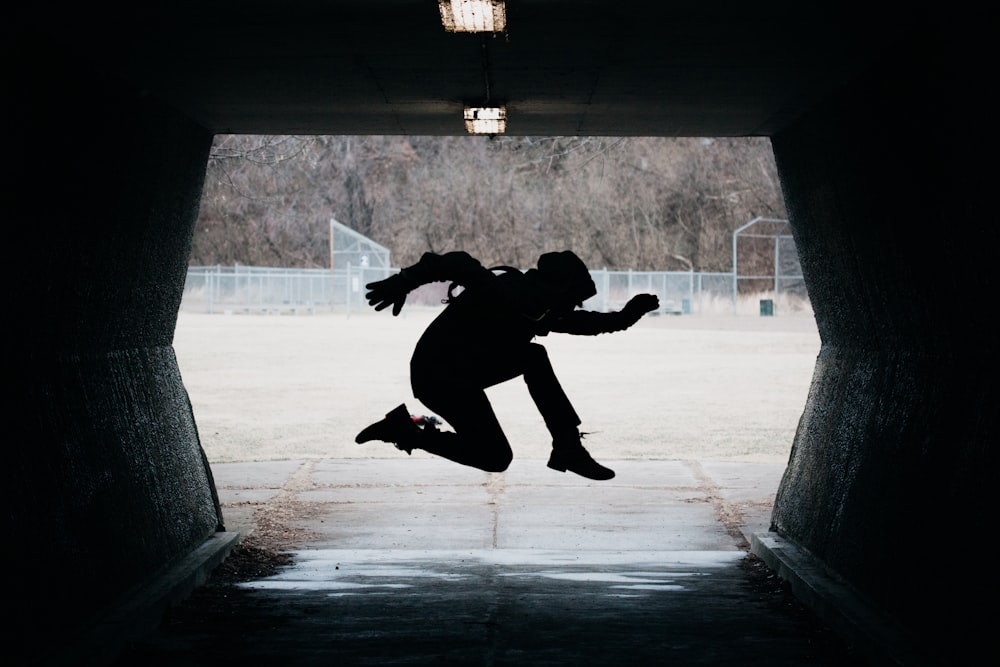 silhouette of man jumping in tunnel