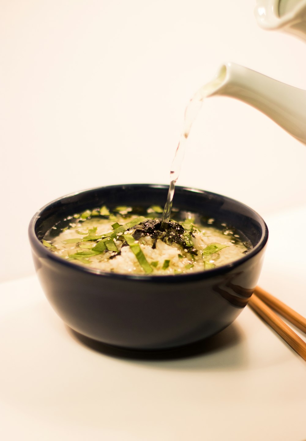 water being poured on black ceramic bowl with soup