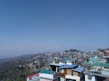 A panoramic view of Shimla town with colorful houses nestled on the hillside.