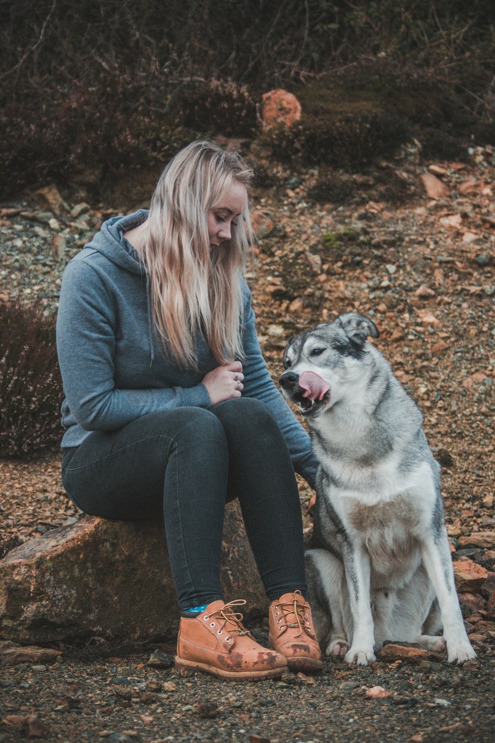 Mujer sentada en la roca junto a su perro