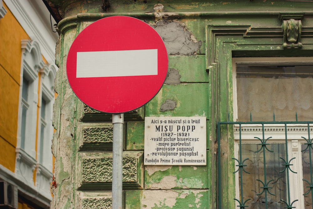 red and white road signage near green concrete structure