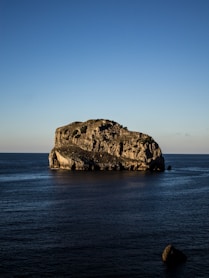 gray boulder on body of water