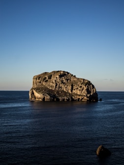 gray boulder on body of water