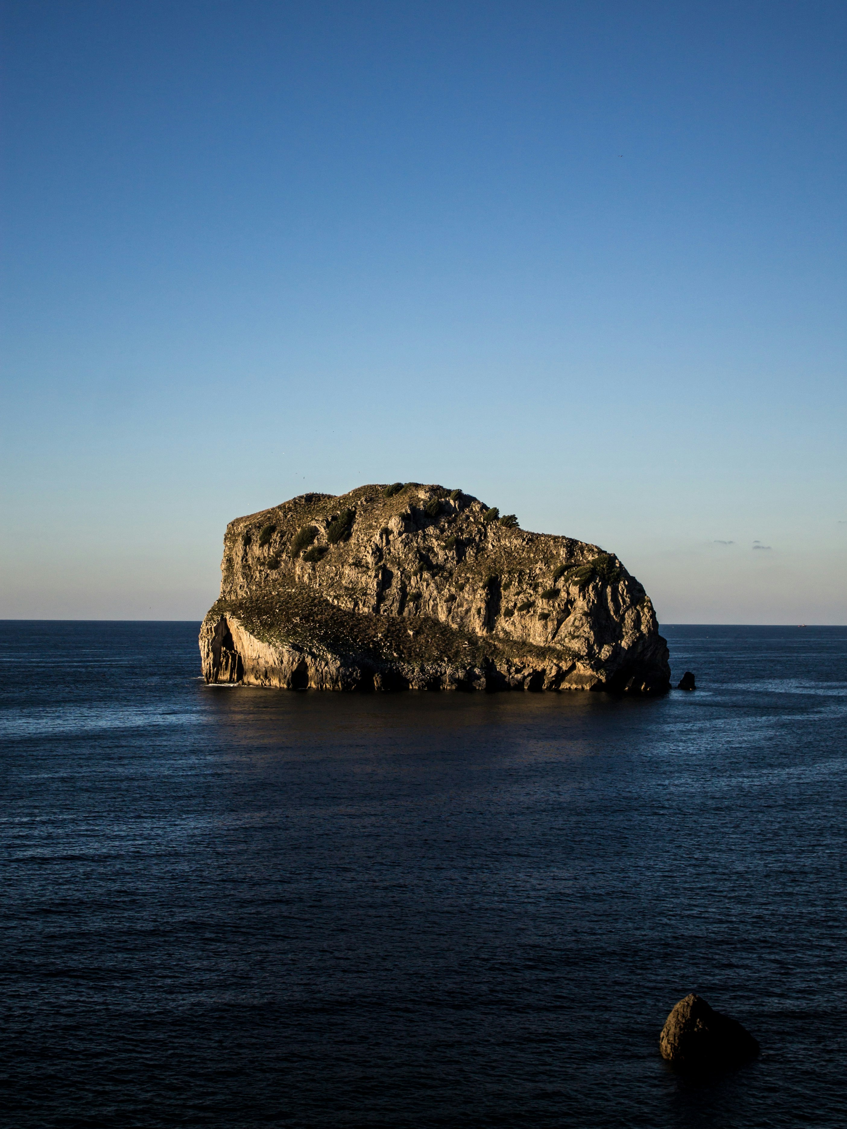 gray boulder on body of water