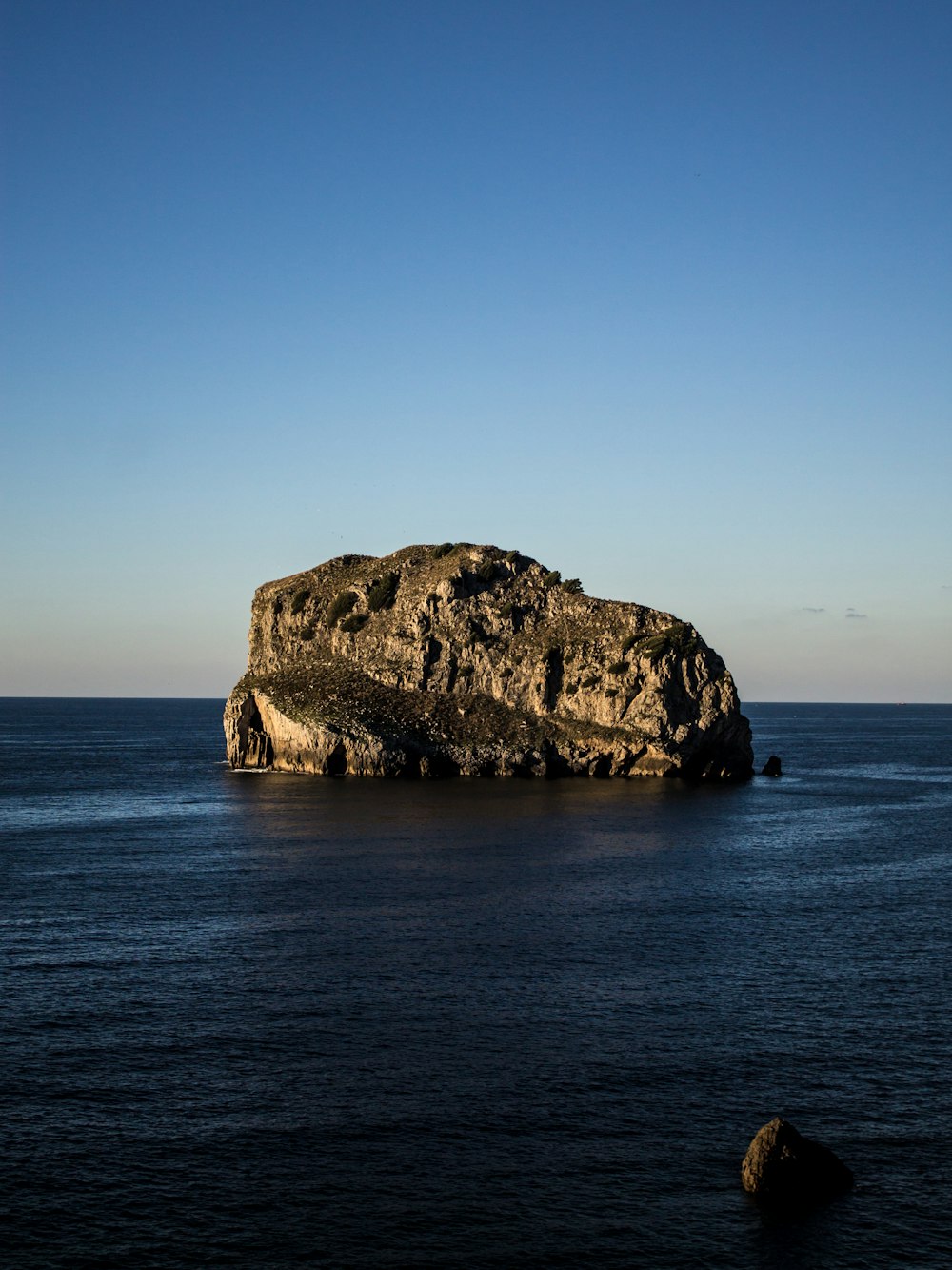 gray boulder on body of water