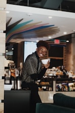 A smiling waiter serving a steaming cup of coffee to a happy customer in a cozy cafe setting.