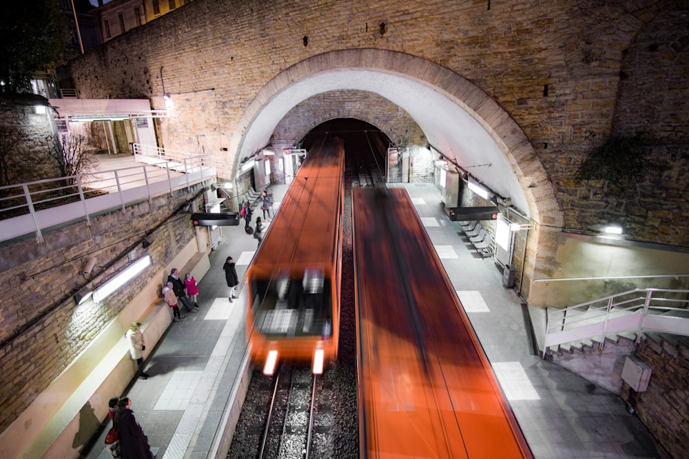 time lapse photography of subway trains passing from and through tunnel