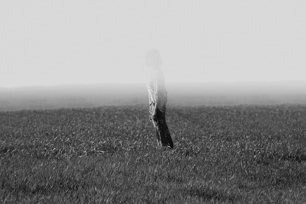 Foto en escala de grises de una persona parada en el campo