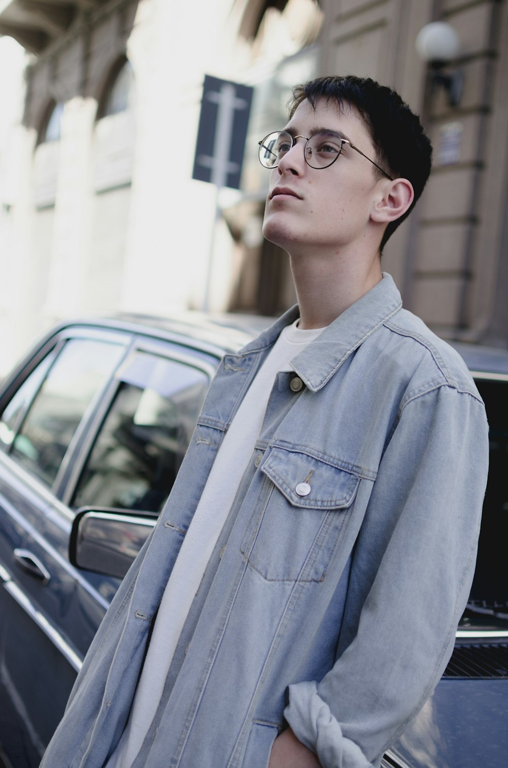 a young man standing next to a parked car