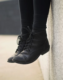 person wearing black lace-up boots