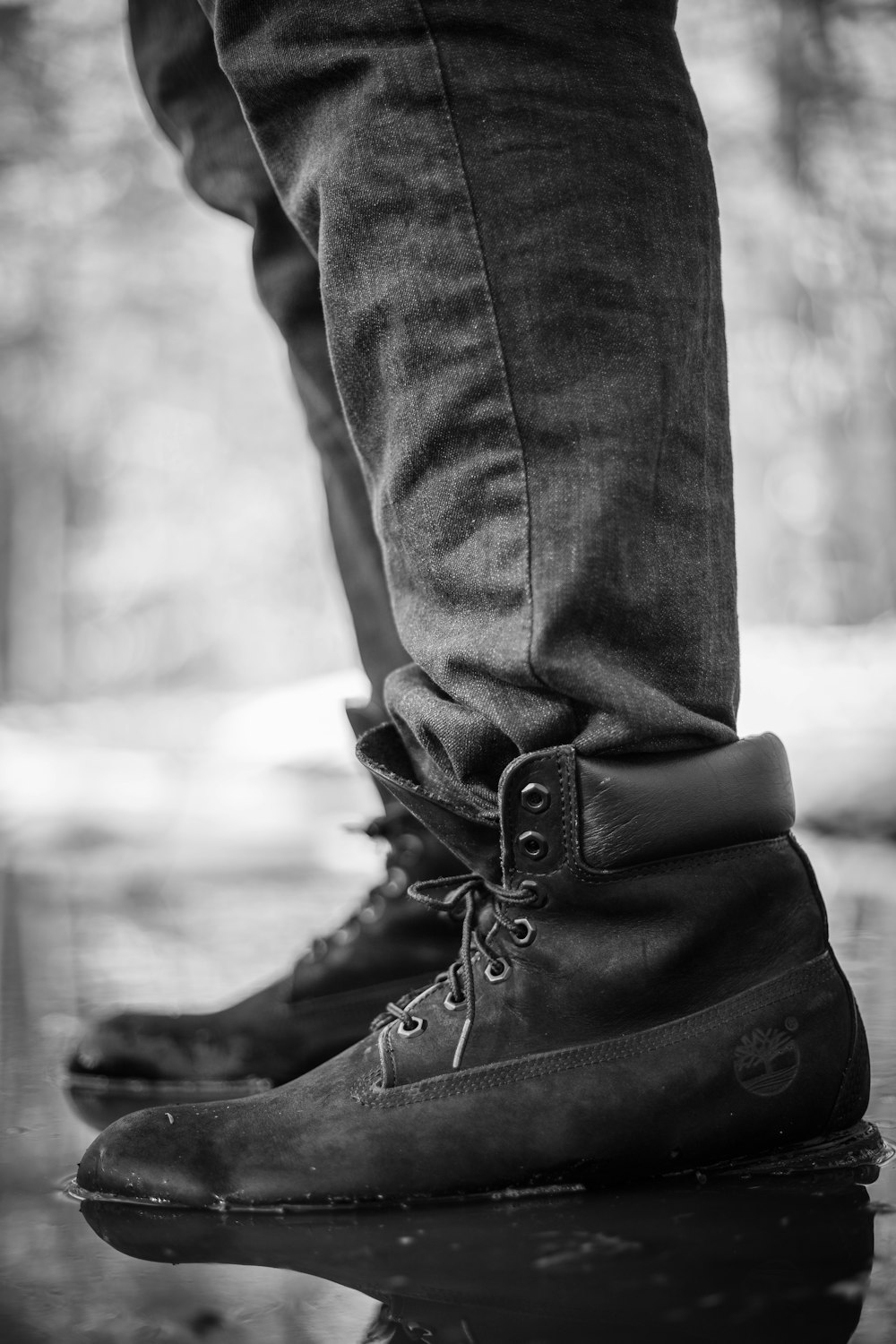 person wearing black Timberland work boots stepping on water