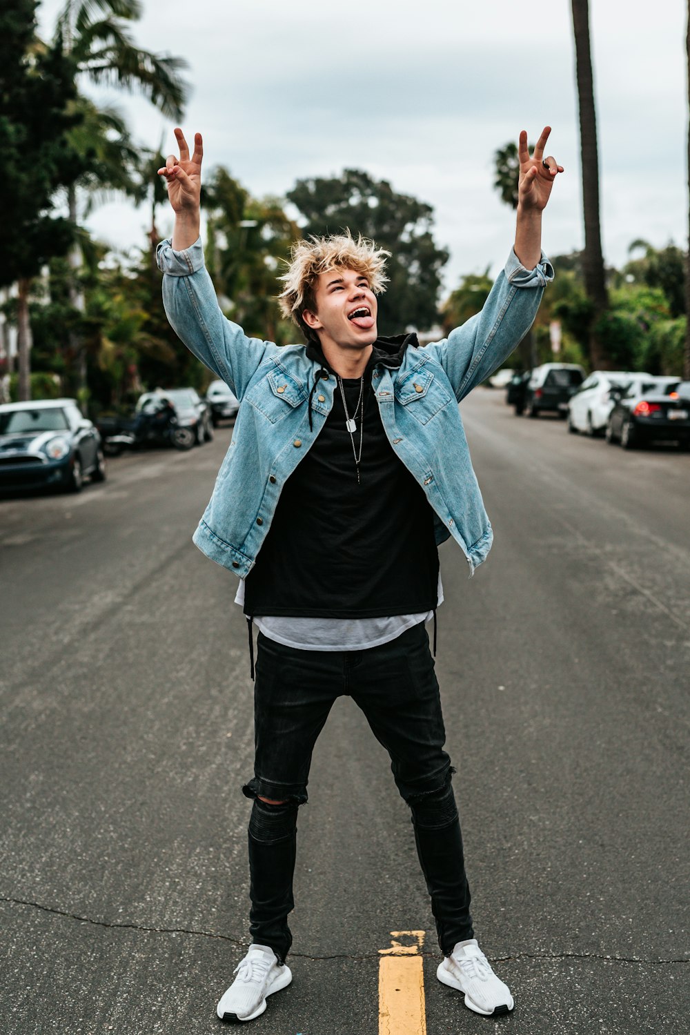 person standing on street raising peace sign