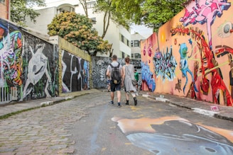 man and woman standing between wall with graffiti artwork