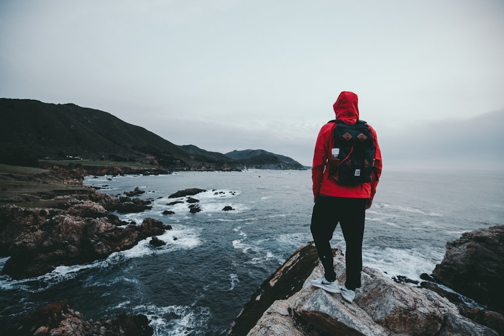 man standing on gray and black rock formation