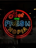 A neon sign displays the words 'Hot and Fresh Hopia' in bright, colorful letters. The sign features a vibrant red border with 'Hot' in red, 'and' in green, 'Fresh' in blue, and 'Hopia' in yellow letters.