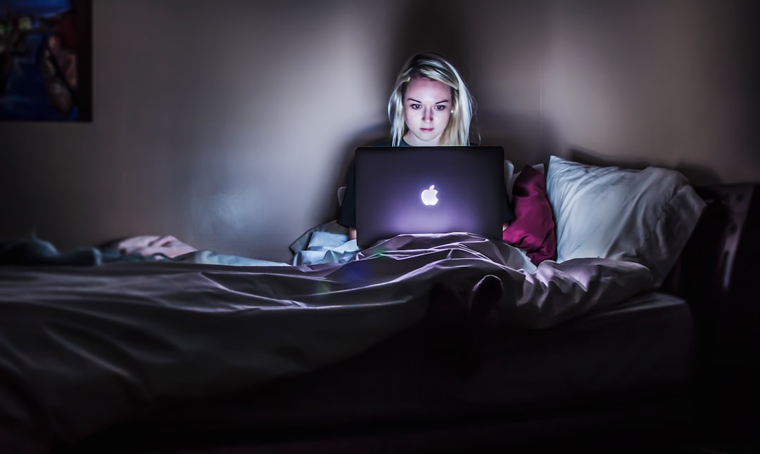 woman sitting on bed with MacBook on lap