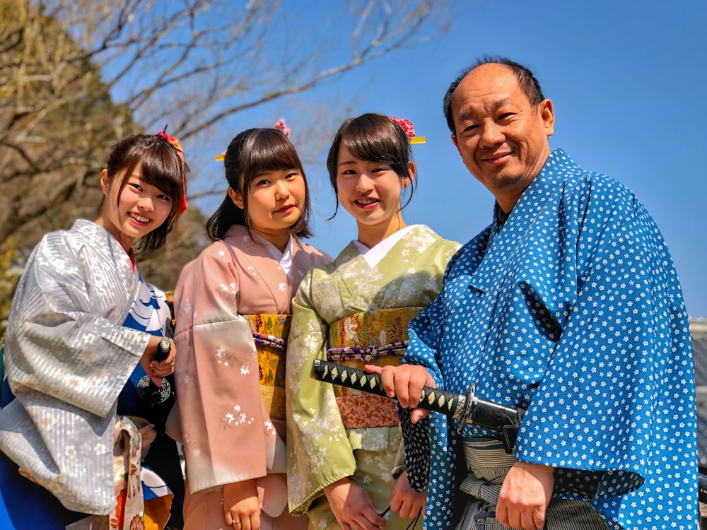Tres mujeres con kimono junto a un hombre que sostiene una espada katana