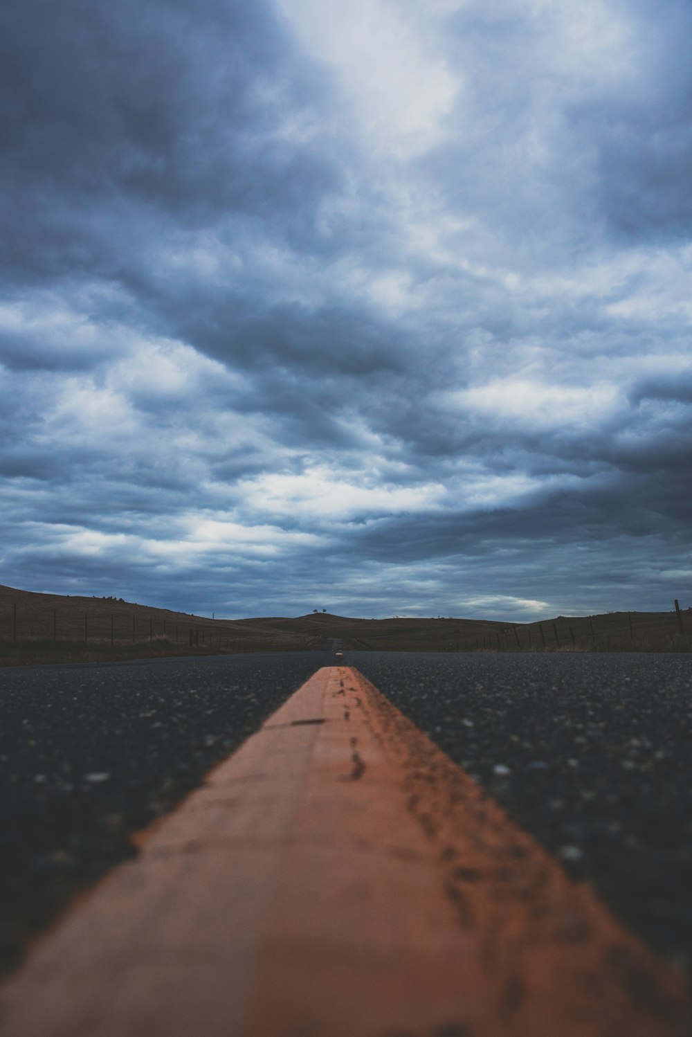 low angle photography of gray concrete road under cumulus clouds