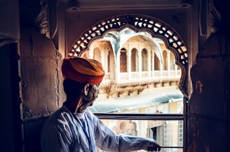 man wearing turban holding on gray metal fence
