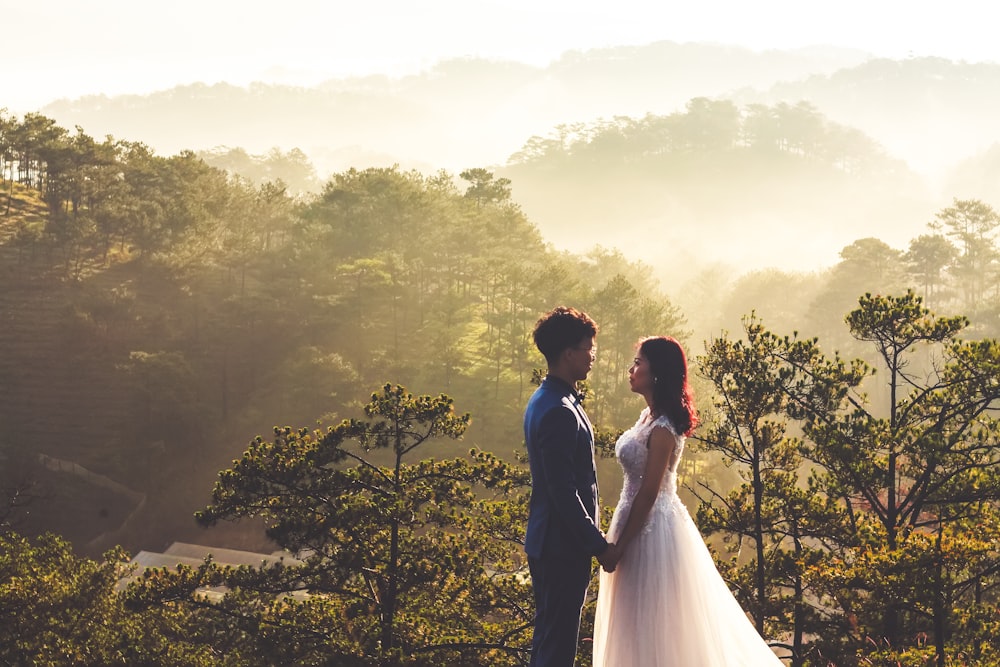 man and woman holding hands near green trees