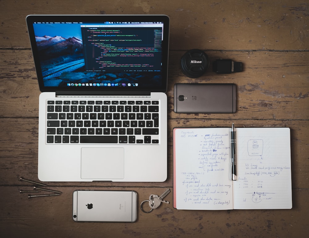a laptop, iPhone, and notebook on a table