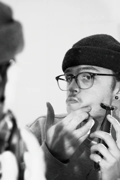 Man using an electric razor with a focused expression in front of a mirror.