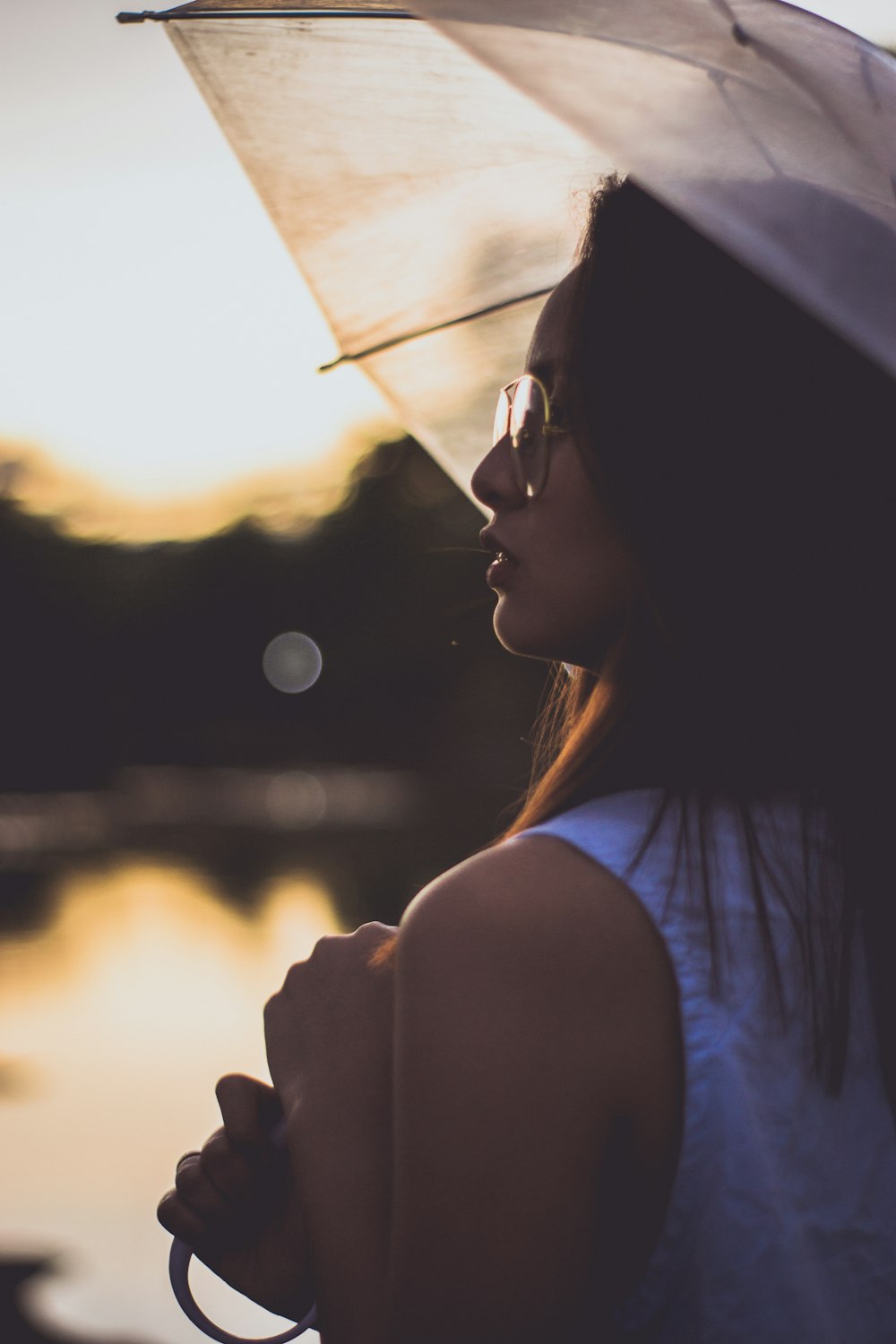 woman in white sleeveless top holding umbrella looking up