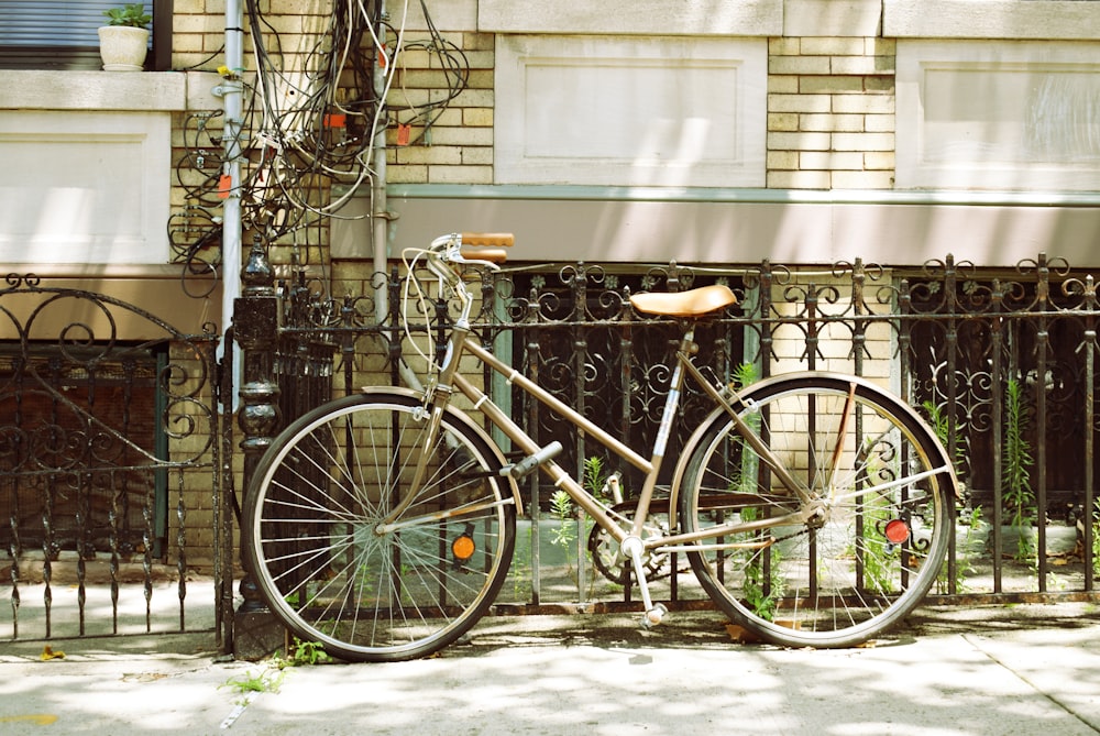 brown city bicycle beside of metal fence