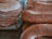 A close-up view of a stack of flatbreads seasoned with sesame seeds, alongside a pile of elongated bread loaves also coated with sesame seeds, displayed on a market stall.