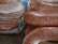 A close-up view of a stack of flatbreads seasoned with sesame seeds, alongside a pile of elongated bread loaves also coated with sesame seeds, displayed on a market stall.