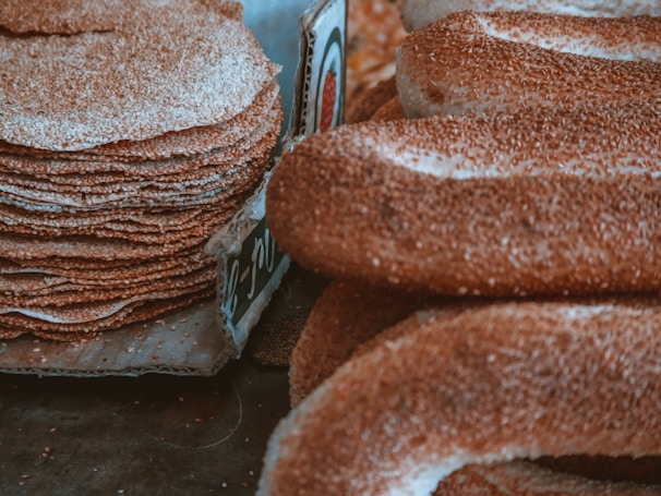 Close-up of hand-rolled flatbreads resting on a woven mat, dusted with flour and sesame seeds.